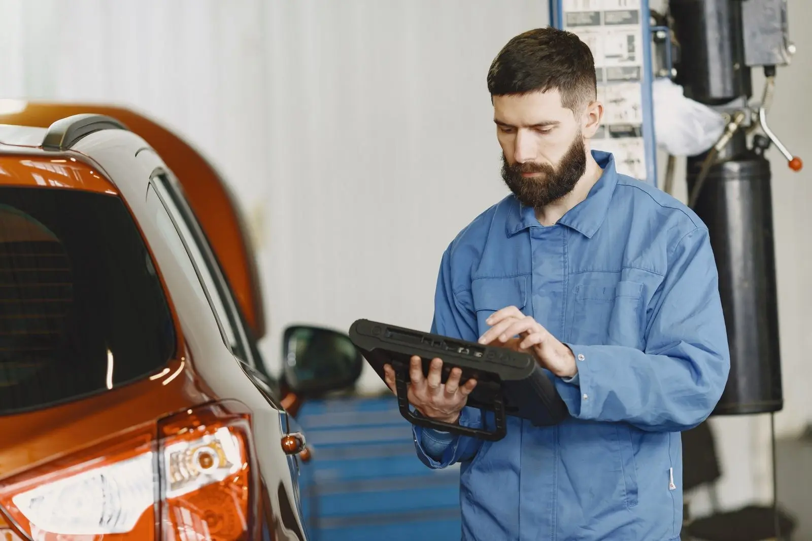 Mecánico revisando un carro con una tableta de diagnóstico